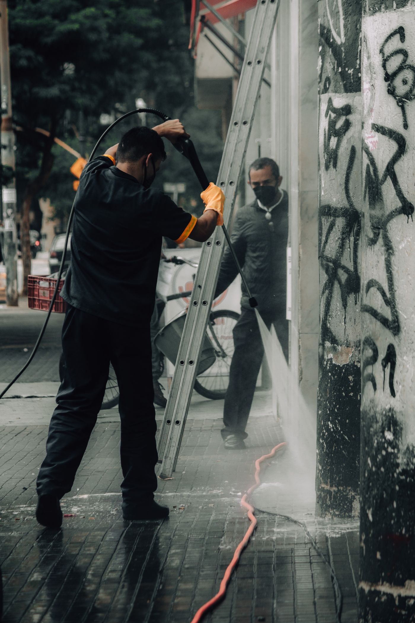 Workers pressure washing a commercial building wall and sidewalk